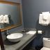Hollywood Palms Inns & Suites Los Angeles bathroom with vessel sink, mirror, toilet, and dark tile floor