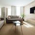 The Preston House and Hotel in Riverhead living room with sofa, coffee table, wall-mounted TV and sunlight