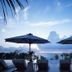 Kafuu Resort Fuchaku Condo Hotel in Onna with ocean-view terrace, lounge chairs, and umbrellas at sunset.