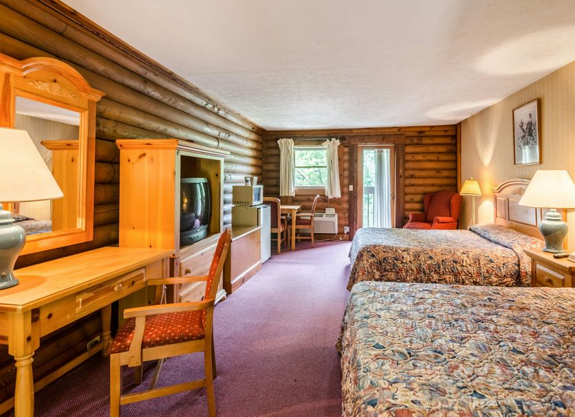 Highland Hills Motel & Cabins in Boone guest room with two beds, desk, TV and log cabin walls