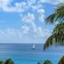 Sapphire Beach Club Resort in Simpson Bay with ocean view, sailboat on calm blue water and palm fronds