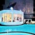River City Hotel in Mukdahan with a lit outdoor pool at night beside a round glass-front building