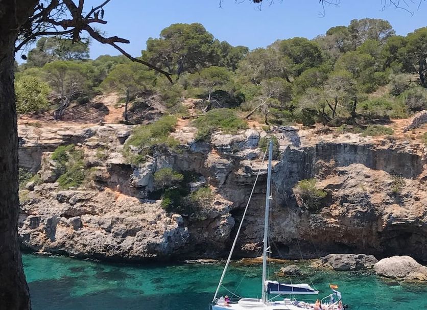 Hostal Atlanta in S'Arenal with rocky seaside cliffs and a small sailboat on turquoise water