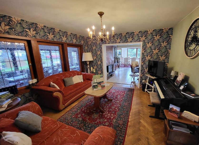 Landhotel Schönblick in Bad Herrenalb living room with sofa, piano, TV and patterned wallpaper