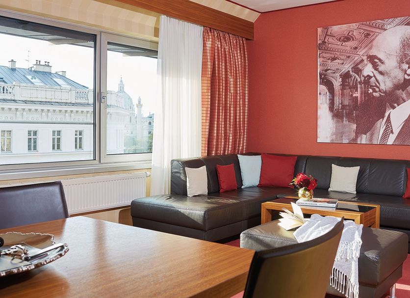 Living Hotel an der Oper in Vienna: suite with city-view window, sectional sofa and large portrait wall art