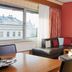 Living Hotel an der Oper in Vienna: suite with city-view window, sectional sofa and large portrait wall art