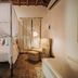 Pousada Terra Madre in Ilhabela: cozy bedroom with canopy bed, armchair, lamp, and bathtub