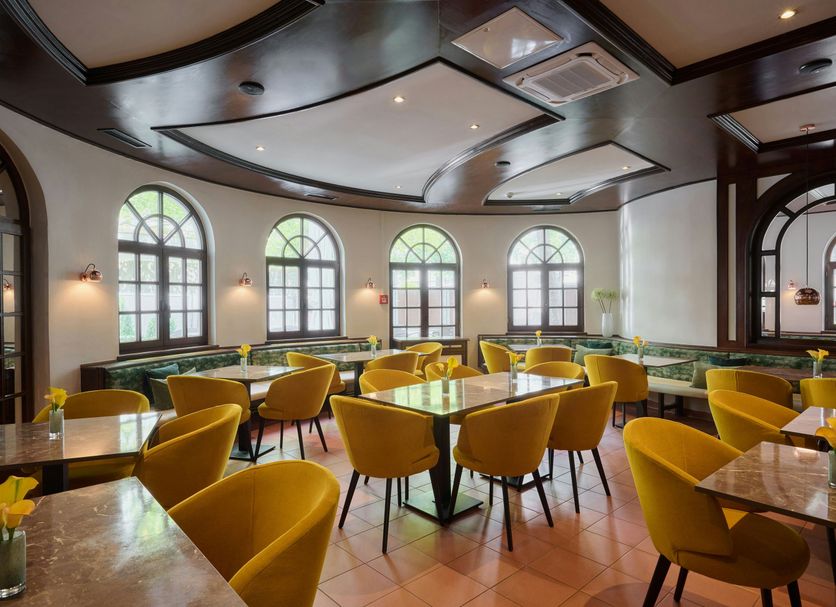 Leonardo Hotel & Residenz München dining room with arched windows and mustard chairs