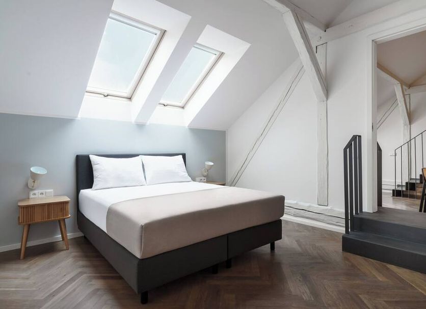 limehome Prague Halkova bedroom with skylight windows, king bed, and loft-style staircase in Prague