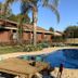 Kingswood Motel in Tocumwal with a curved outdoor pool, palm trees, and sun loungers beside brick units.