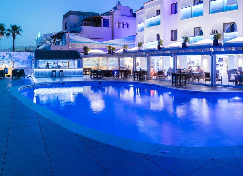 Apartamentos Sal Rossa in Sant Josep de sa Talaia with a lit outdoor pool and beachfront terrace at dusk