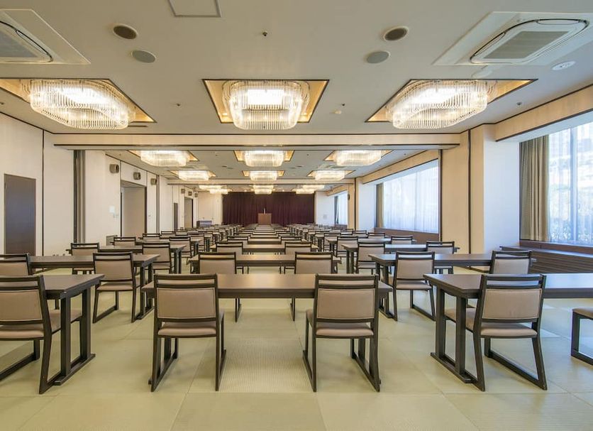 New Welcity Yugawara meeting room with rows of tables and chairs, large windows, and ceiling lights