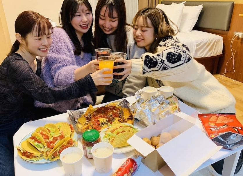 Hotel Trad Osaka guests toasting drinks beside a room-service meal in a guest room