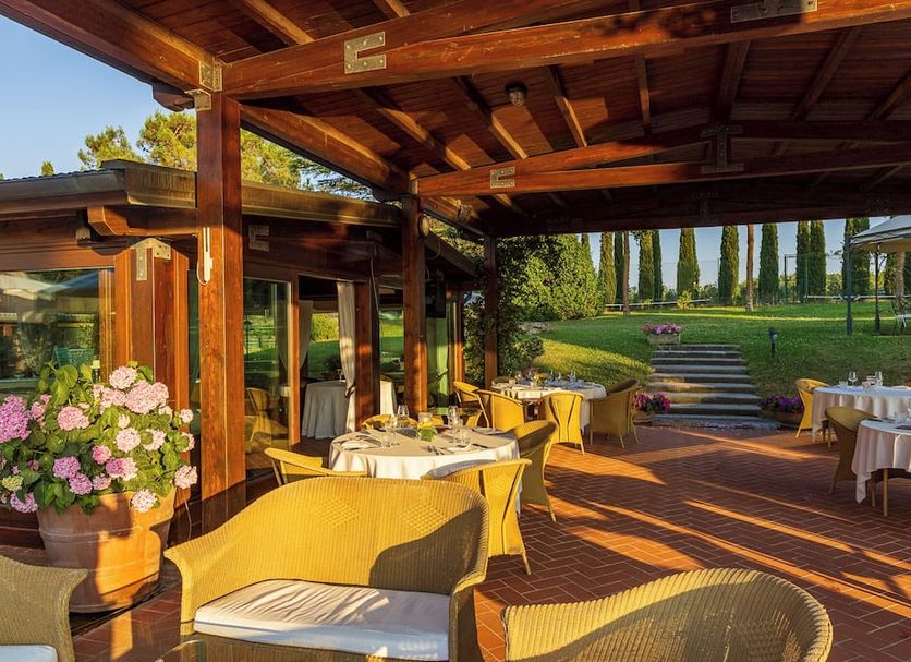 Open-air dining terrace at Agriturismo La Sovana in Sarteano with garden views and set tables