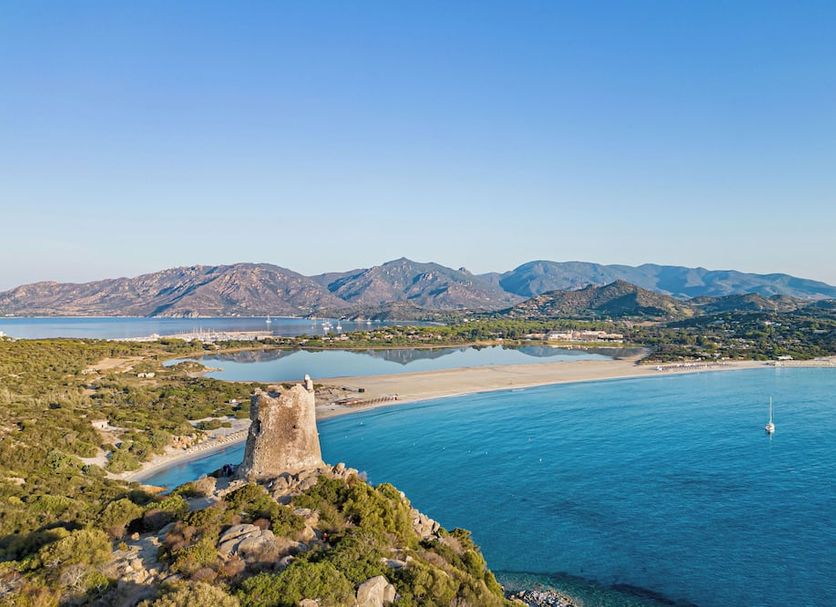 Almar Timi Ama Villasimius overlooking a turquoise bay, beach, and coastal mountains in Villasimius