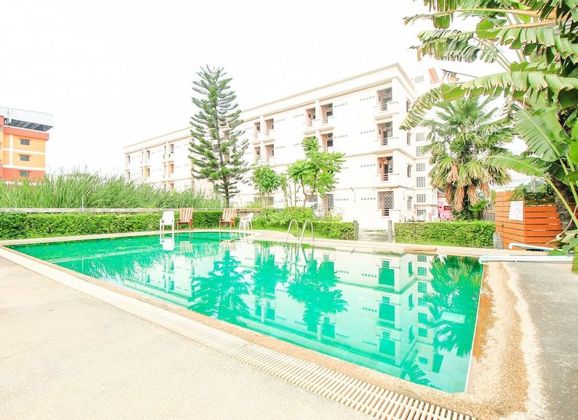 Ok Home Airport, Bangkok: outdoor swimming pool beside low-rise hotel buildings and greenery