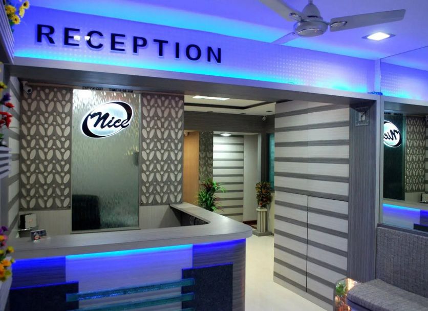 Nice Guest House Mumbai reception desk with blue lighting and mirrored wall