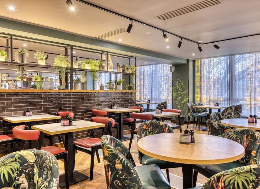 Premier Inn Glasgow - Cambuslang/M74 J2a dining area with round tables, tropical chairs and large windows
