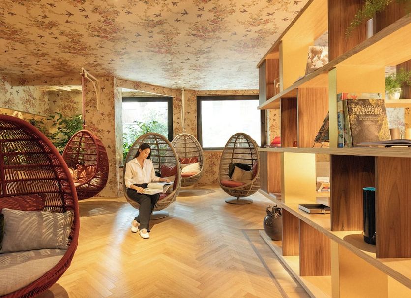 Qc Room Milano Porta Romana in Milan lounge with hanging egg chairs and a person reading