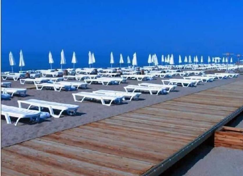 Lara Kapris Hotel in Antalya beach area with rows of sun loungers, umbrellas, and wooden walkway
