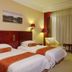 Gold River Side Hotel in Jiaxing room with two twin beds, wall art, lamps and a curtain-covered window