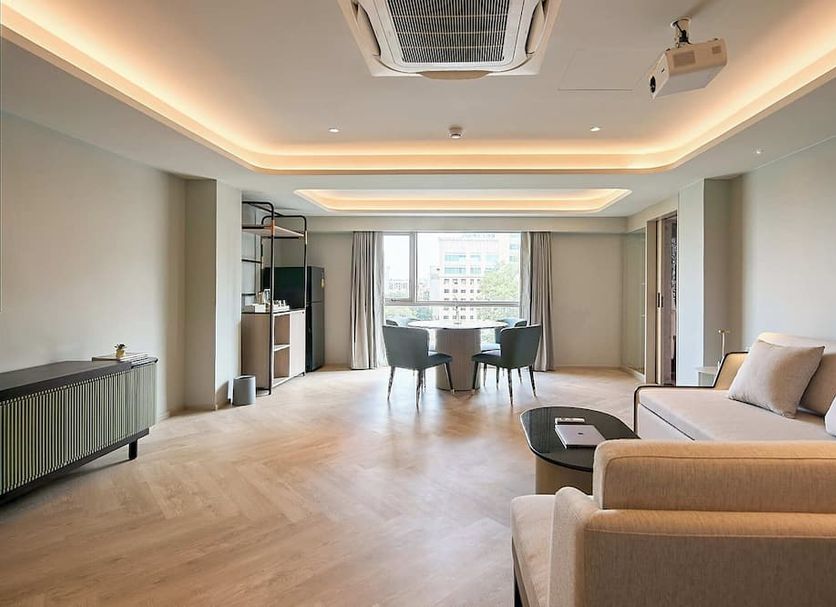 The Path Siam Bangkok suite with seating area, dining table and city-view windows
