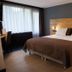 Hotel Bieze, Borger: modern guest room with double bed, wood headboard, desk and large window