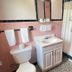 Best Motel Bowling Green bathroom with pink tile, vanity sink, toilet, mirror, shower curtain, and tub