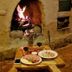 Refugio Del Pintor in Tilcara: cozy stone hearth with fire and a small table set with food and wine.