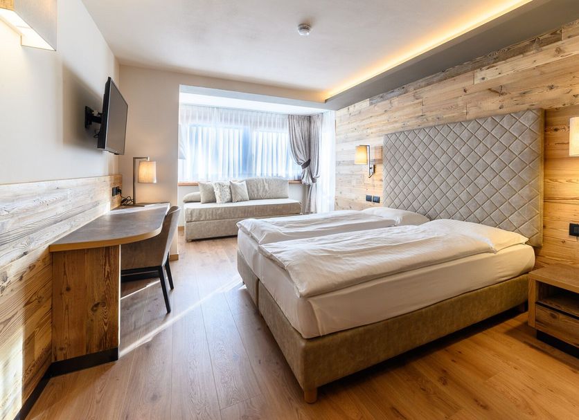 Hotel Crozzon in Madonna di Campiglio guest room with twin beds, sofa and window seating area