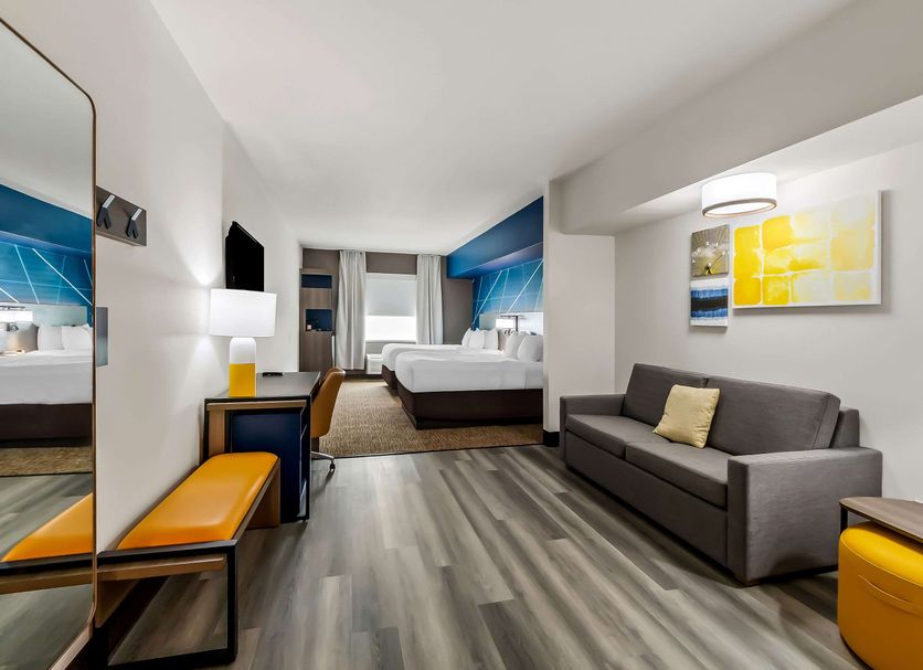 Comfort Inn & Suites Donna guest room with sofa, two beds, desk, mirror and bright yellow accents