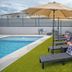 Casa Toñita in Levittown: poolside lounge chairs with umbrella beside an outdoor swimming pool