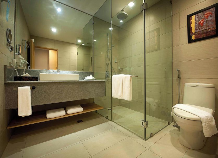 Berjaya Makati Hotel bathroom with glass shower, vanity, and toilet in Makati