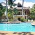 Mike's Dauin Dive Resort in Dauin: tropical pool with palm trees and thatched-roof cabanas