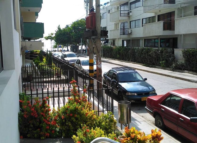Hotel Betoma in Santa Marta street view with parked cars, sidewalk flowers, and nearby buildings