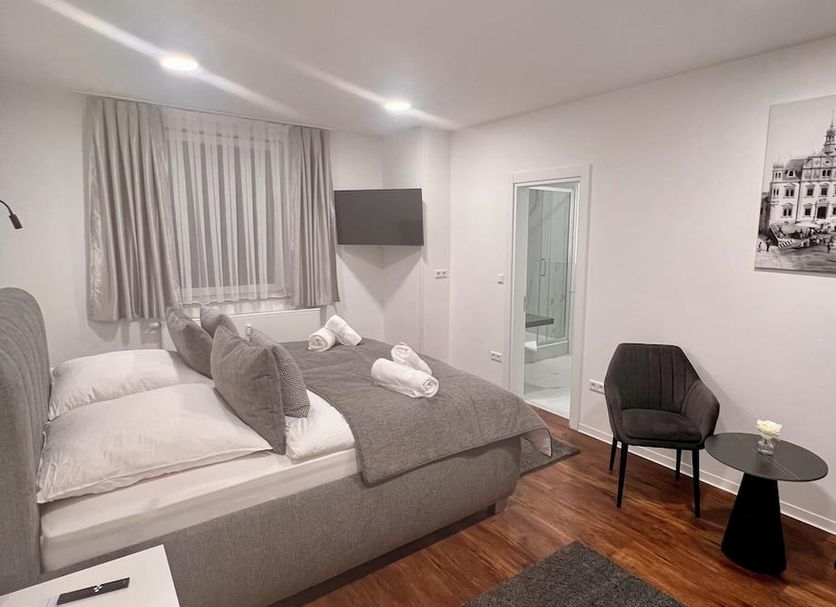 Hotel am Schlossplatz Hechingen guest room with double bed, chairs, small table, and bathroom doorway