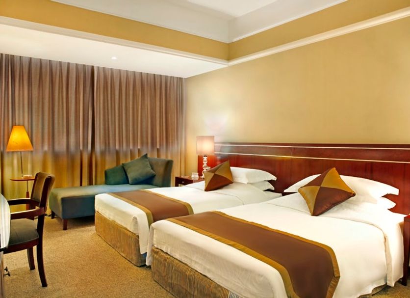 Rosedale Hotel Shenyang guest room with two twin beds, sofa, desk and warm lighting in Shenyang