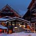 Chalet Hotel Régina in Les Gets, snow-covered alpine lodge lit up with festive string lights