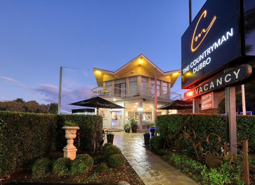 Countryman Motor Inn in Dubbo at dusk, with lit entrance, hedges, and vacancy sign