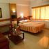 Hotel City Tower Coimbatore guest room with bed, sofa, desk, mirror, and large window with curtains