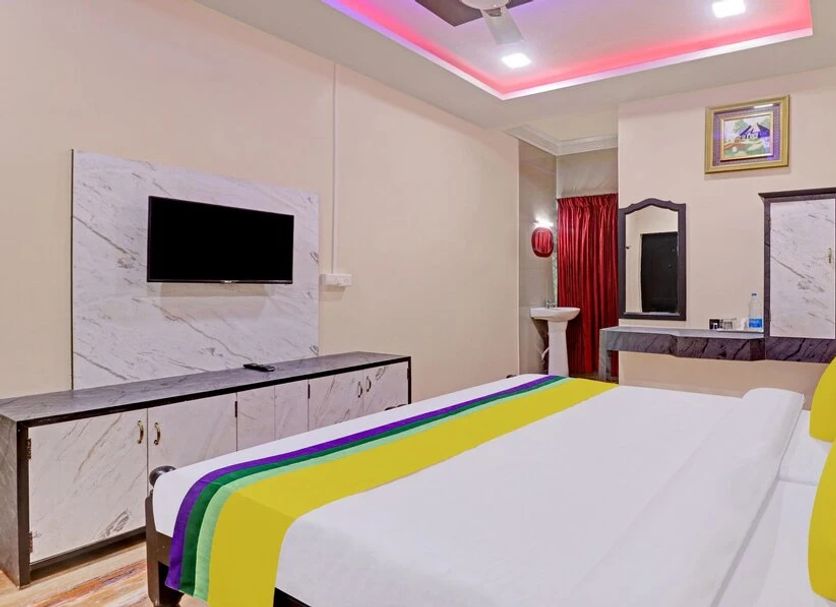 Hilltown Hotel Madikeri guest room with double bed, wall TV, vanity, and red curtains