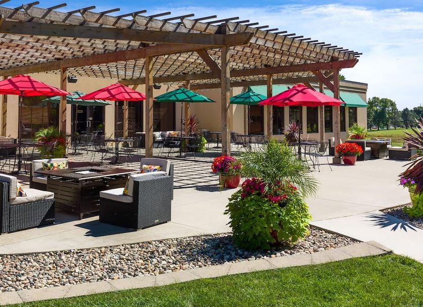 Lake Okoboji Resort and Conference Center patio with pergola, seating, umbrellas, and landscaping in Okoboji