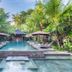 Kejora Suites in Denpasar with tropical outdoor pool, loungers, umbrellas and palm trees