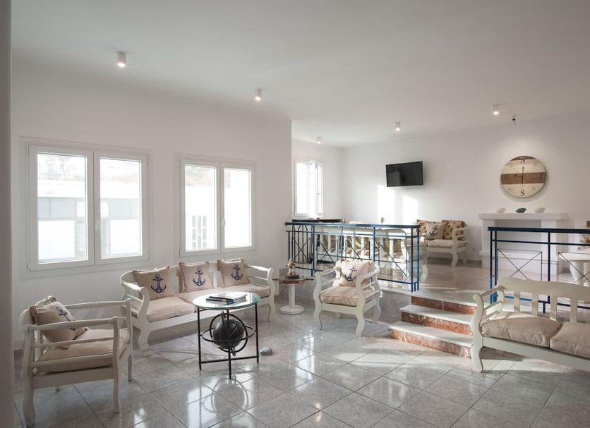 Capetan Giorgantas in Adamantas: bright lounge with sofas, chairs, glass table and raised seating area
