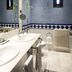 Bathroom at Parador de Jarandilla de la Vera in Jarandilla de la Vera with double sinks, blue tile and radiator.