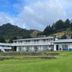 Lottin Point Motel in Hicks Bay with white beachfront buildings and green hillside backdrop