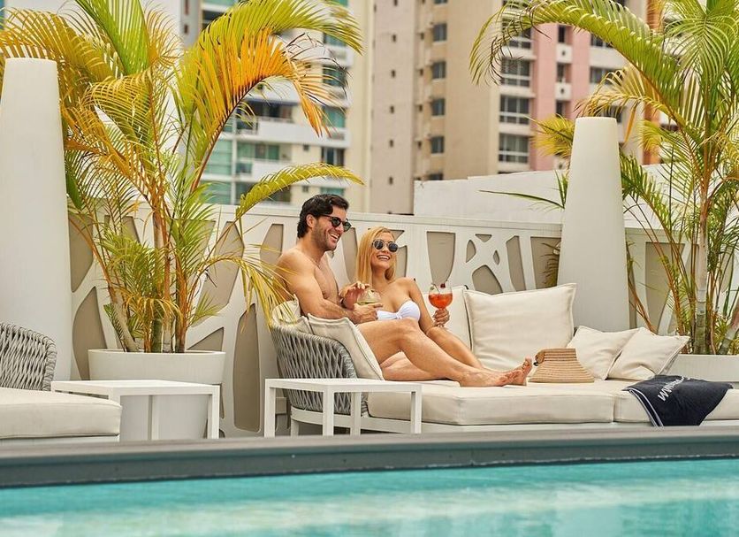 Gran Evenia Panama rooftop pool lounge with couple relaxing and city skyline in Panama City