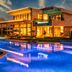 Kaya Palazzo Golf Resort in Belek with illuminated outdoor pool and modern resort buildings at dusk