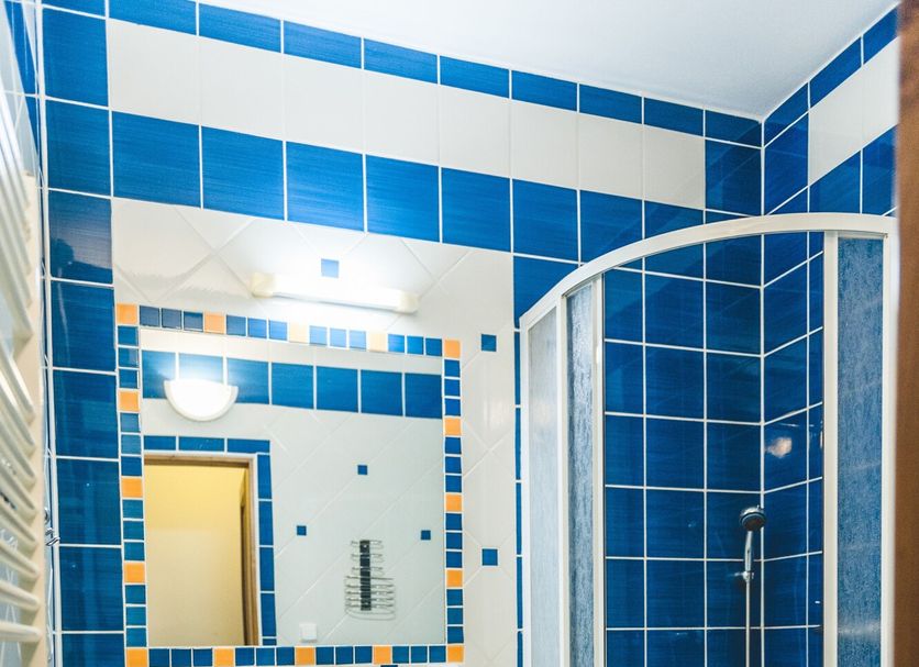 Hotel u České Koruny bathroom with blue tile, pedestal sink, mirror and curved glass shower in Hradec Králové