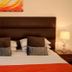 Kingsland Hotel London guest room with king bed, dark headboard, bedside lamps and orange bed runner